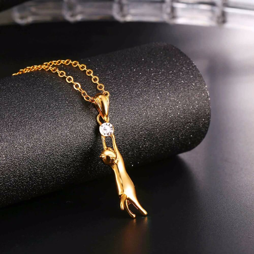 golden cat necklace on black surface kittysensations