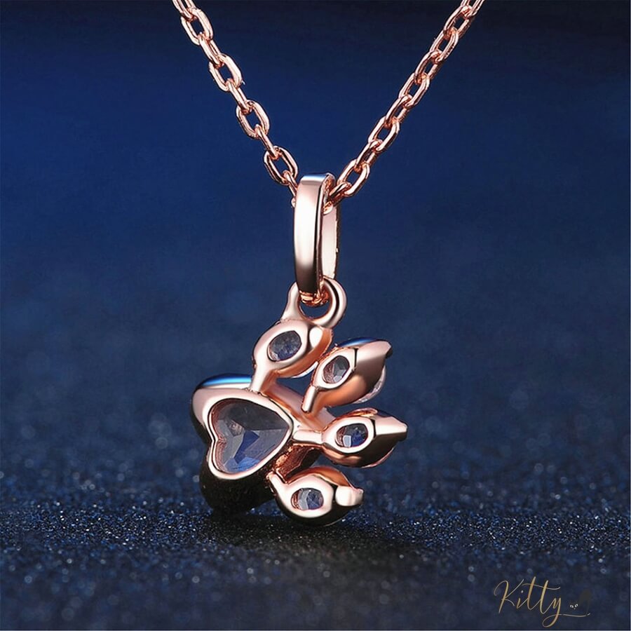 back of cat paw necklace in rose gold on blue surface 13405465-pink